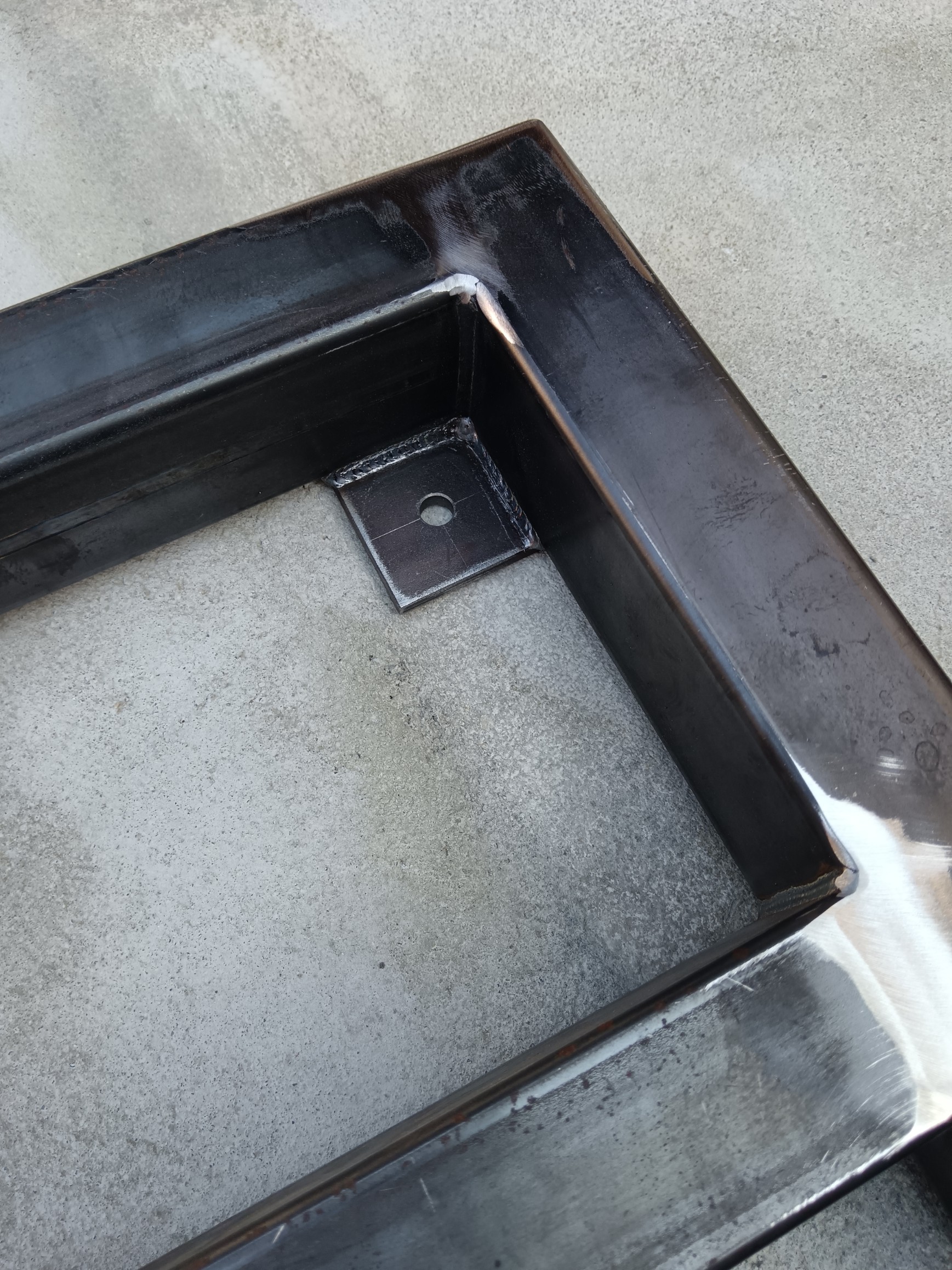 Functional corner detail of an industrial welded skid frame with integrated mounting plate and bolt hole. The joint reflects practical design, stable construction and careful fabrication suited to repeatable industrial work.